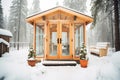 pine wood sauna with glass door amid snow-covered trees Royalty Free Stock Photo