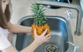 Pineapple being cleaned and washed in a kitchen sink. Wash food. Child hands holding tasty fresh pineapple. Healthy lifestyle.