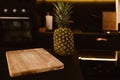 Pineapple in a black luxury Kitchen near a wooden board for cutting vegetables