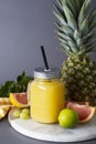 Pineapple cocktail or juice in glass jar bottle with straws and fruits on background - pineapple, oranges, grapefruit, lime and Royalty Free Stock Photo