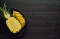 Pineapple cut in black bowl on dark wooden background. Copy space Royalty Free Stock Photo