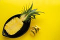 Pineapple cut in black ceramic bowl on yellow background Royalty Free Stock Photo