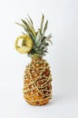 Pineapple decorated like a Christmas tree. Gold beads garland. Golden shining reflective disco ball. White background