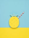 Pineapple figurine with a cocktail tube on a blue and yellow background. Minimal summer concept
