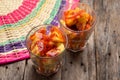 Pineapple cutted with chili powder and piquant sauce in glass on wooden background