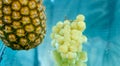 Pineapple and grapes dipped in water at the same time