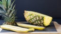 A pineapple half on a stone-framed stone board is cut in half, about two halves of a banana Royalty Free Stock Photo