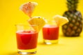 Pineapple juice in glass closeup near sliced fruit with spash and dripping liqid for summer vibes