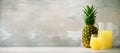 Pineapple juice in glassware and whole pineapple fruit on gray background. Copy space, sunlight effect. Summer, holiday Royalty Free Stock Photo