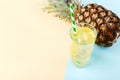 Pineapple and juice with ice in a glass, on a blue yellow background. Summer mood, copy space