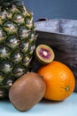 a pineapple near an orange, a full kiwi and a chopped red kiwi.