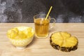 Pineapple slice with chopped skin, bowl with peeled pineapple cubes