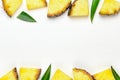 Pineapple slices with green leaves of pineapple on a white wooden background frame. Tropical juicy exotic healthy fruit