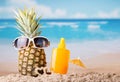 Pineapple with sunglasses, umbrella and sunscreen, on beach Royalty Free Stock Photo