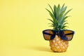 Pineapple with sunglasses on yellow background