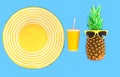 Pineapple with sunglasses and yellow straw beach hat cup juice on blue background Royalty Free Stock Photo