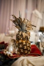Pineapple on the table with a tablecloth and with a small figurine of a gnome