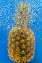 Pineapple under water covered with bubbles and with bubbles in the background blue