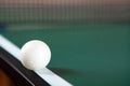 A ping pong ball on the edge of a green ping pong table. Close-up. Ping-pong net Royalty Free Stock Photo