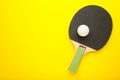 Ping pong paddle with ball on yellow background. Table tennis racket Royalty Free Stock Photo