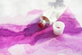 Pink acrylic paints tubes and hand drawn abstract magenta watercolour drawing picture on white textured paper background