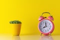 Pink alarm clock with cactus in pot on wooden desk. Minimal time concept Royalty Free Stock Photo