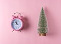 Pink alarm clock with Christmas tree on pastel pink background. Minimal Christmas concept Royalty Free Stock Photo