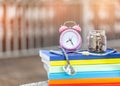 Pink alarm clock closeup standing on pile of books. Business Royalty Free Stock Photo