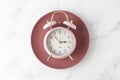 Pink alarm clock on retro red plate on white marble table background. Time to food Royalty Free Stock Photo