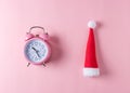 Pink alarm clock with Santa Claus hat on pastel pink background. Minimal Christmas concept Royalty Free Stock Photo