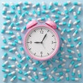 Pink alarm clock on top view with capsule pills spread on the floor. Health care remind you to take your medicine on time. Royalty Free Stock Photo