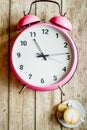 Pink alarm clock on wooden table with coffie top view Royalty Free Stock Photo