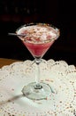 Pink alcohol cocktail in glass with high leg with black straw on white napkin on table Royalty Free Stock Photo