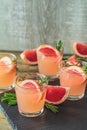 Pink alcoholic cocktail with grapefruit, ice and rosemary