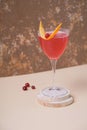 Pink alcoholic cocktail in steamed glass on wooden podium or pedestal