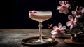 Pink alcoholic cocktail in a tall glass on a black background with delicate flowers.