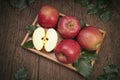 San Fuji Apples in wooden basket on wooden table in garden, Pink Apple with leaves in wooden background.
