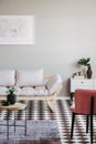 Pastel pink armchair and beige scandinavian futon in trendy living room interior with black and white floor Royalty Free Stock Photo