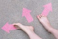 Pink Arrow Choice Concept. Female Bare Feet with Pink Nail Polish Manicure Standing and Many Direction Arrows Choices on the Road