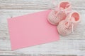 Pink baby booties with pink greeting card on weathered wood Royalty Free Stock Photo