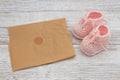 Pink baby booties with paper on weathered wood Royalty Free Stock Photo