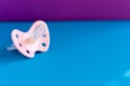 Pink baby pacifier on blue background for copy space, mother`s day, celebration card for newborn Royalty Free Stock Photo