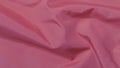 Pink background from crumpled, wavy fabric. Soft focus