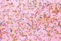 Pink background flat lay with sweet multicolored sprinkles flat lay