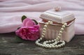 Pink background with gift box and pearl beads and a rose, mother day, symbols of love Royalty Free Stock Photo