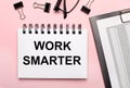 On a pink background, reports, black paper clips, glasses and a white notebook with the text WORK SMARTER Royalty Free Stock Photo