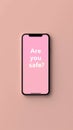 pink background with smartphone displaying the safety question 'are you safe', emphasizing concern and Royalty Free Stock Photo
