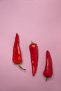 On a pink background there are three bright red fresh peppers Royalty Free Stock Photo