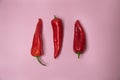 On a pink background there are three bright red fresh peppers Royalty Free Stock Photo