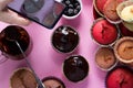 On a pink background a woman`s hand shoots cupcakes on a smartphone camera with chocolate and berries